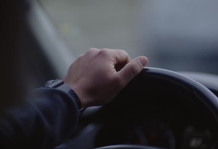 A man waves his arm while driving