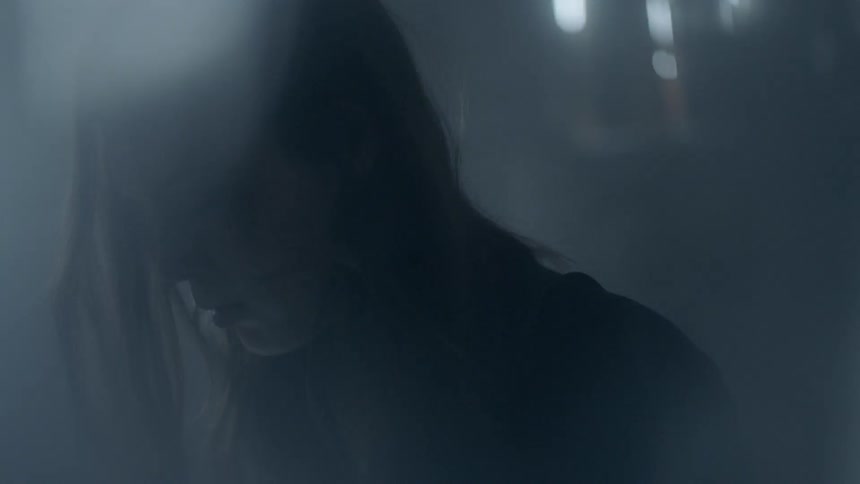 A woman looks down in a dark room