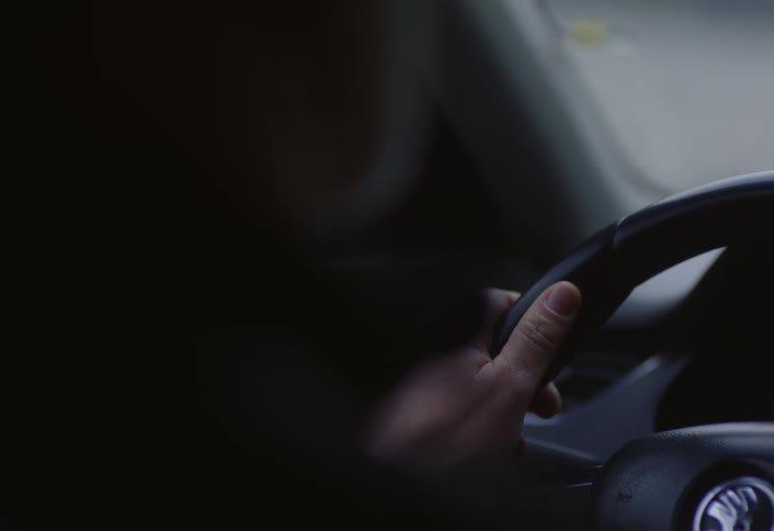 A mans hand is gripping a steering wheel while driving the car