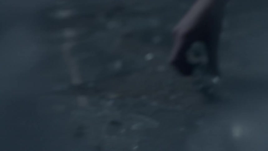 A woman picks up pieces of glass from the ground