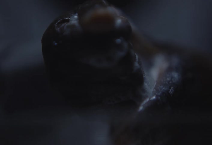 A closeup of hands washing in soapy water with foam in a bowl set in a dimly lit room