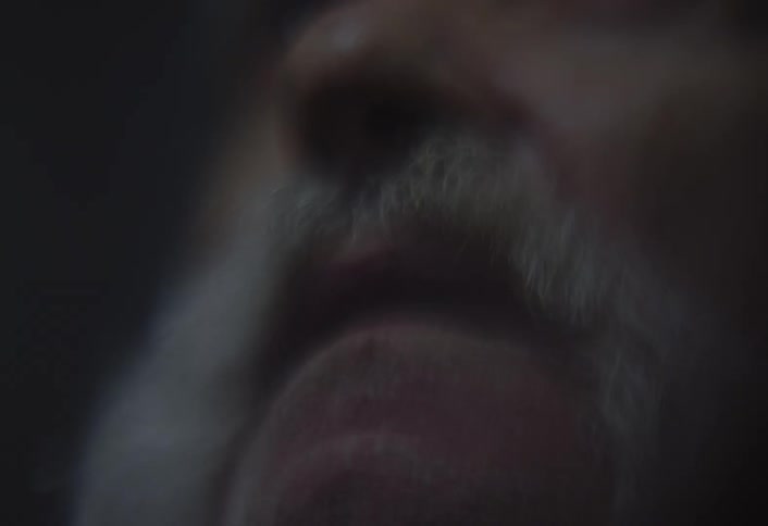 A man is holding a lit cigarette close to their mouth taking a puff