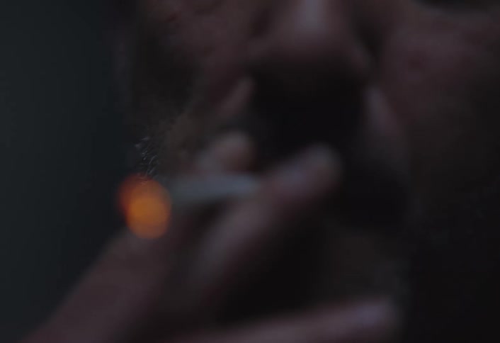 A man is smoking a cigarette in the dark
