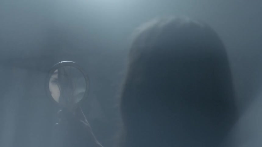 A woman in a room looking through a handheld mirror