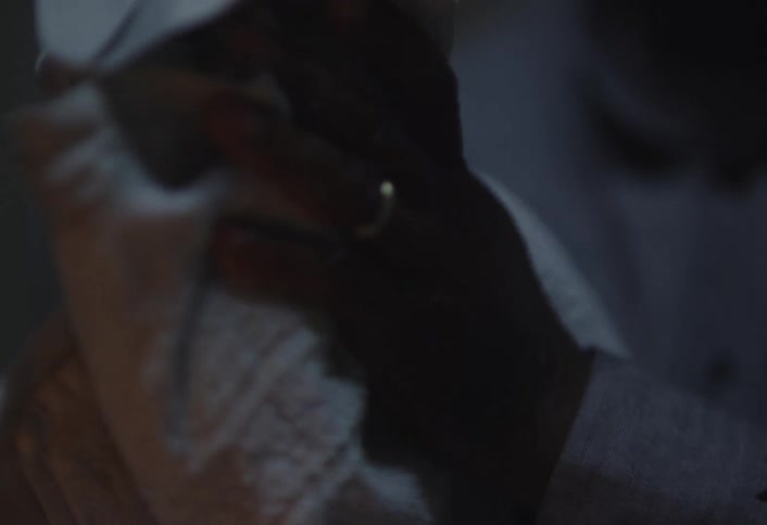 Close up of a person drying his hands with a white towel on a dimly lit room