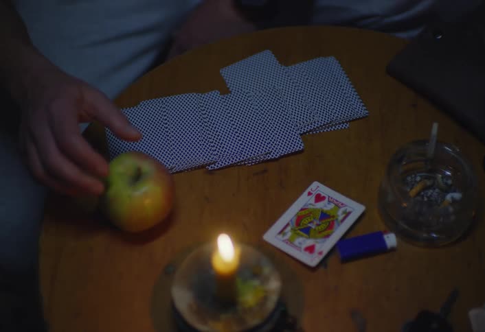 A person puts a card on the table and eats an apple