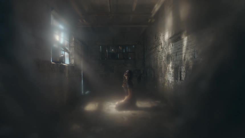 A woman kneeling in a building where sun is entering the window