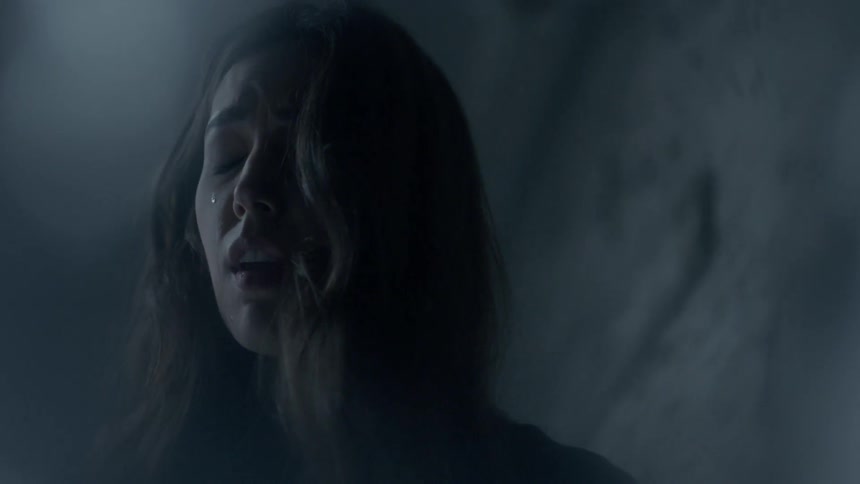 A woman is in a dark room crying