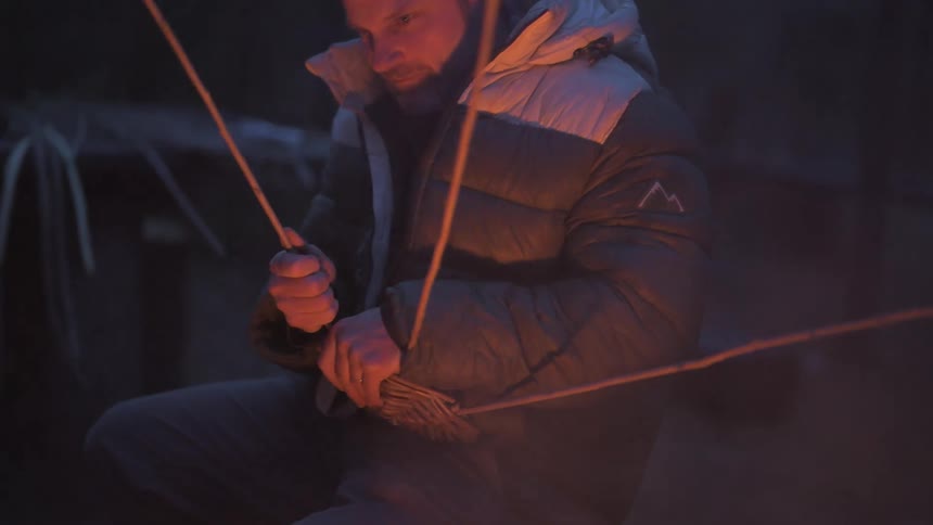 A man is building a trap with sticks