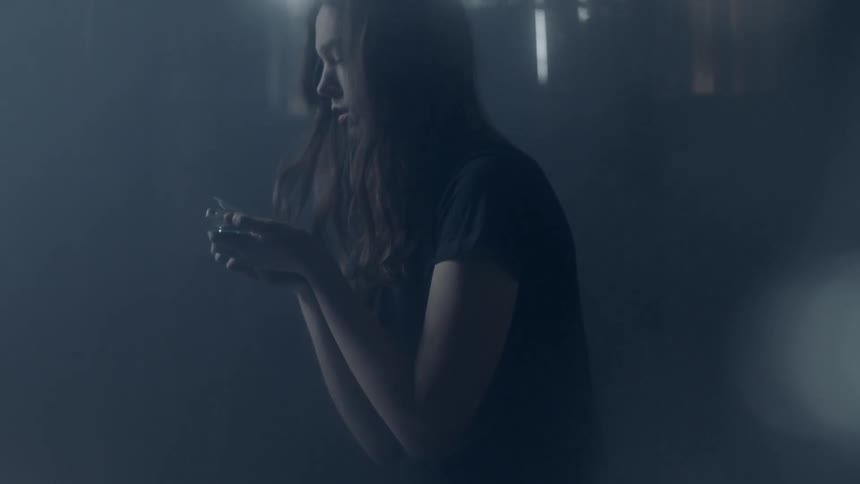 A woman is kneeling down with a hand full of glass