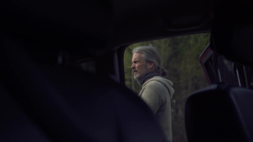 Man pulling out a rifle from car in the forest