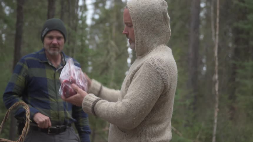 A man is packing meat into plastic bags on the campsite