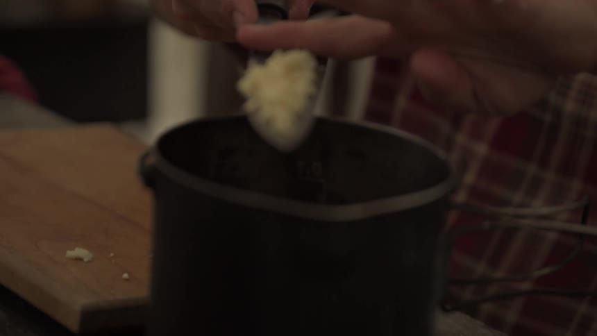 A man puts garlic in the pot