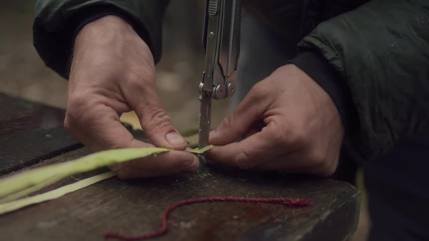 A man is cutting straw with a multi tool