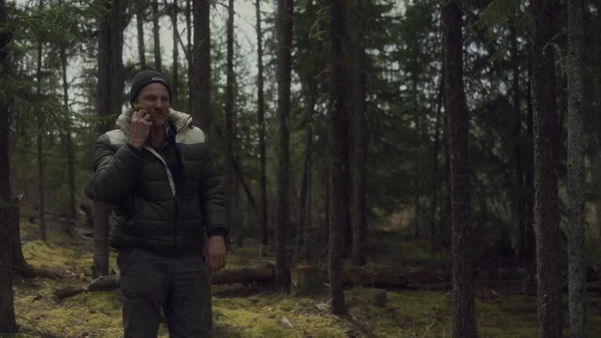 A man wipes his face in the woods