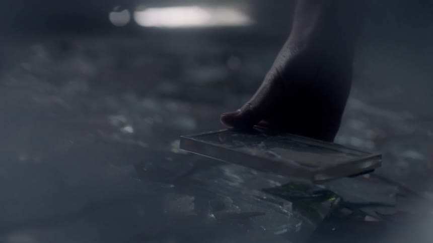 A person picks up a picture frame from a debris covered floor