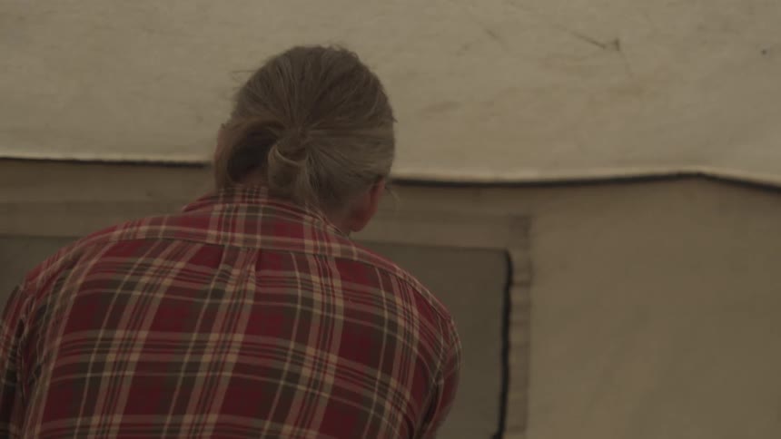 Older man moves back and forth while near a tent