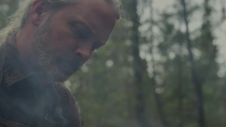A man gets up from the campfire