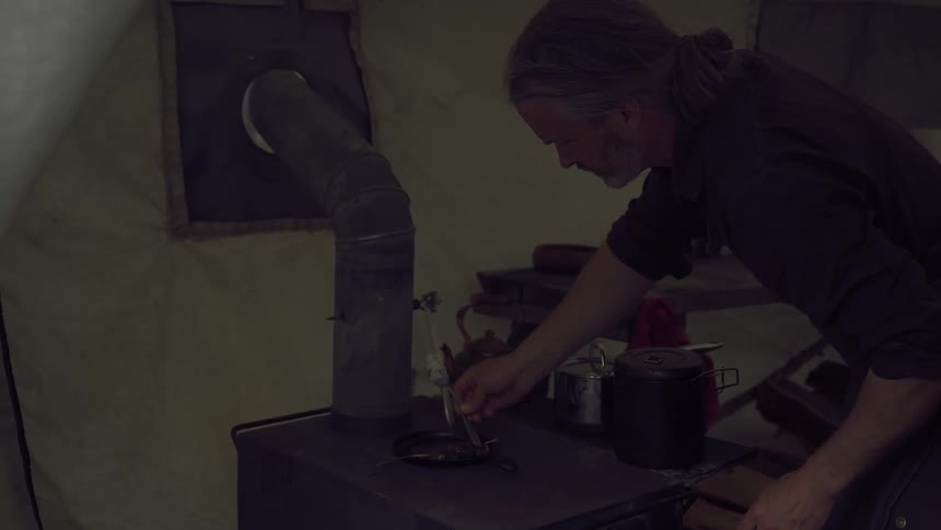 A man is cooking in a tent and mixing food