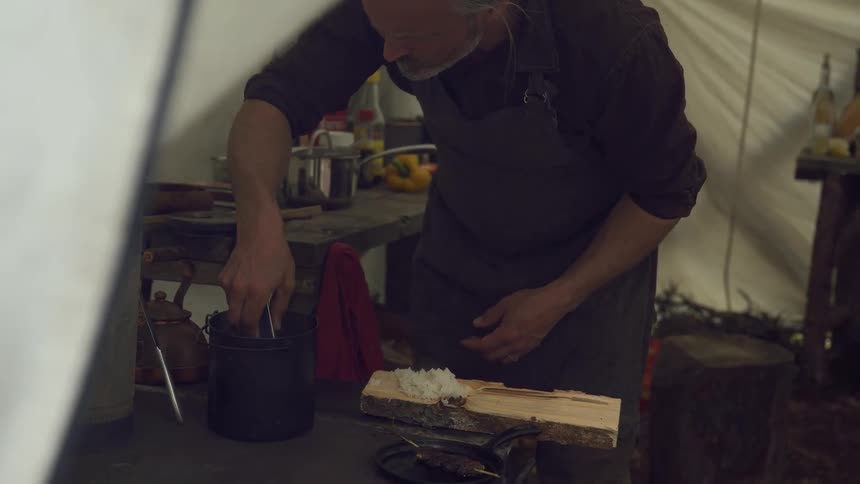 A man carefully places cooked meat on the rice