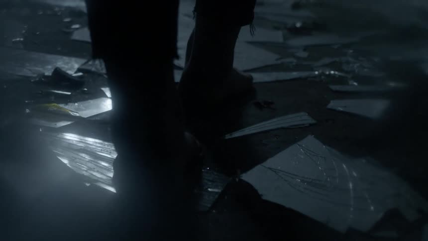 Bare feet walk across broken pieces of a mirror