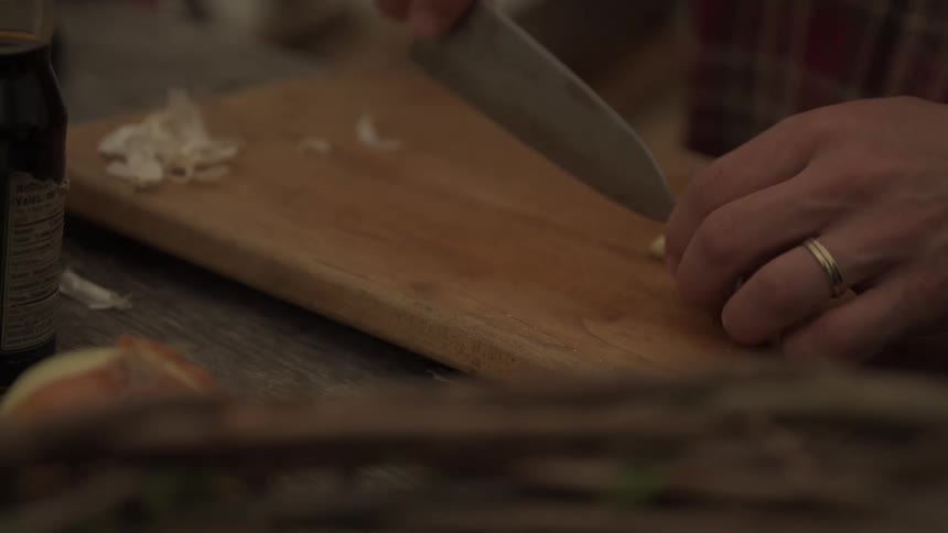 Man slices garlic while cooking outdoors during the daytime