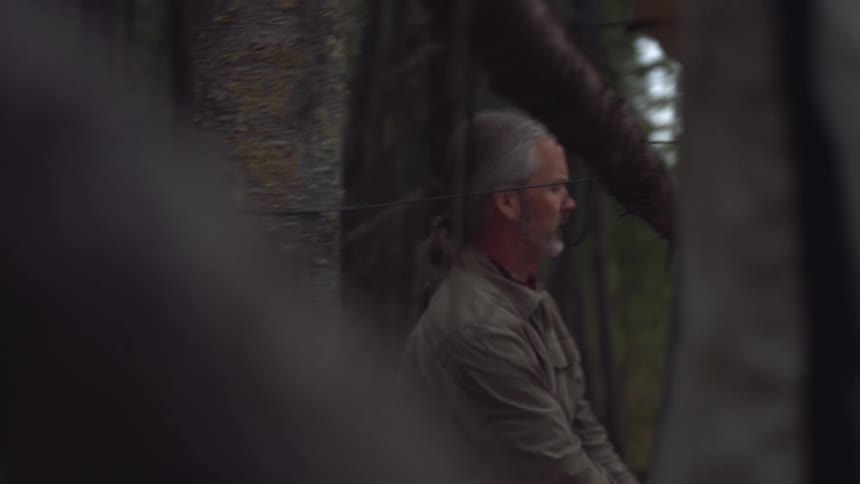 A man ties the ropes while setting up a tent