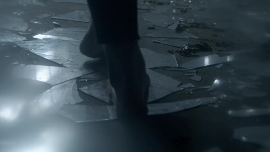 A person walking barefoot across broken glass on the floor