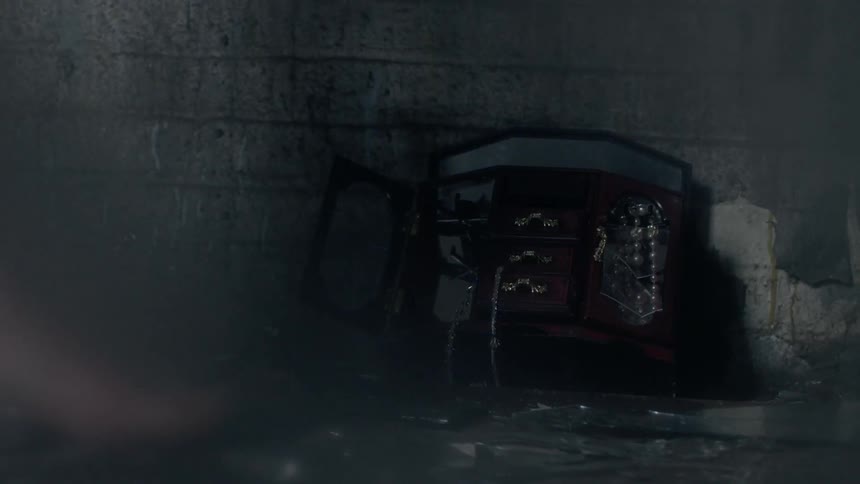 A barefooted woman walks by a smashed jewelry box lying on the ground