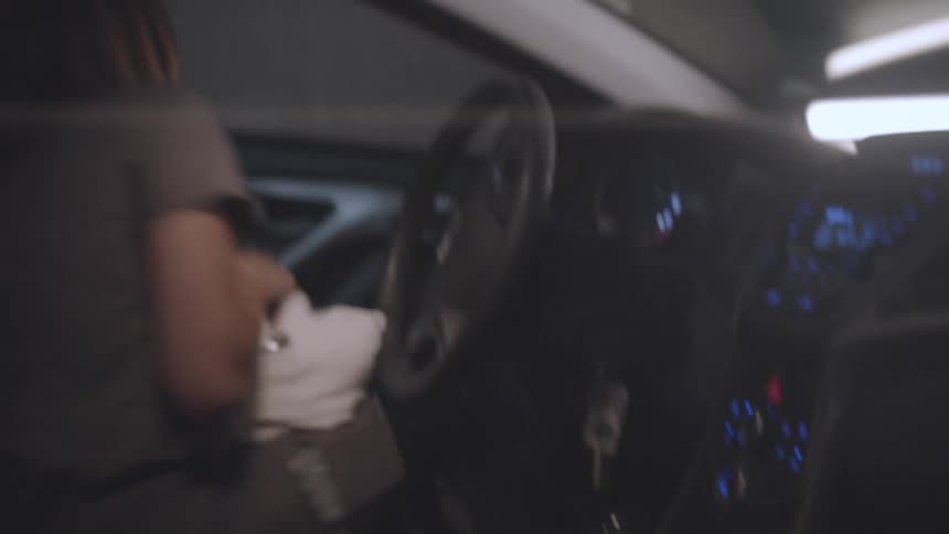 A woman picks up her lab coat and exits the car