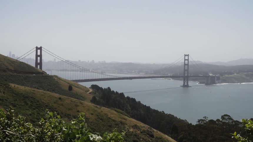 A large bridge is surrounded by hills in the background