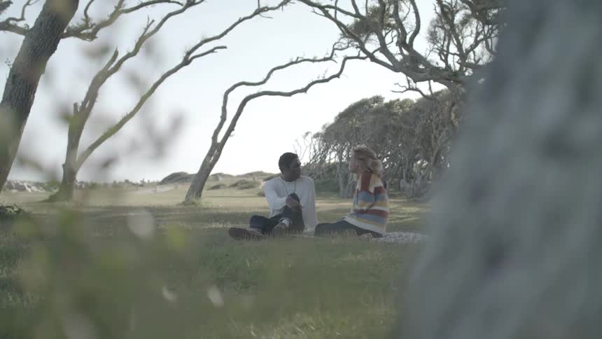 Two friends talking to each other while sitting down at the park
