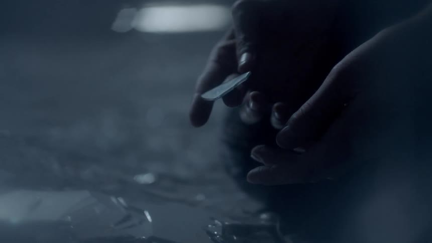 A person holding a shard of glass and touching it