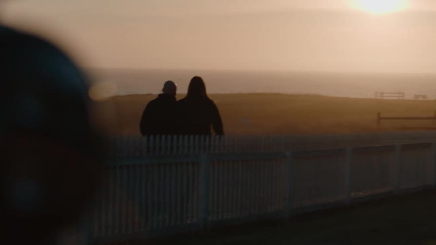 A couple walk towards the lighthouse on a foggy day
