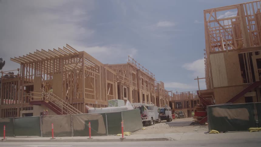 Traffic passes by as homes are being built
