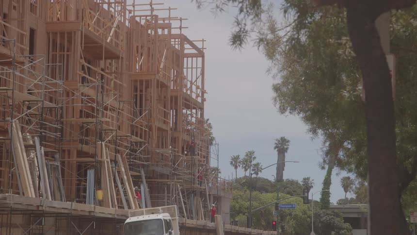 Construction workers carry lumber on the work site