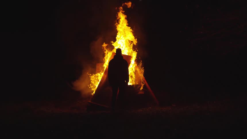 Someone is watching objects burn in a fire at night