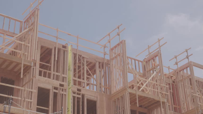 A worker is up on the scaffolding working on a home frame