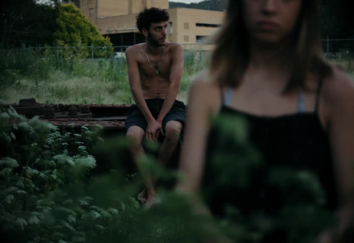 A man sits down near the grass on a windy day