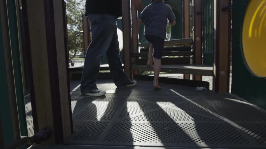 Man and boy climb on playground equipment