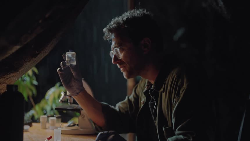 A scientist looks at a vial in the tent