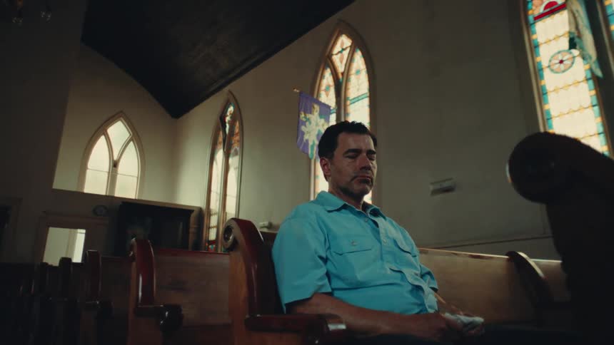 Sad man sitting alone in a pew at church