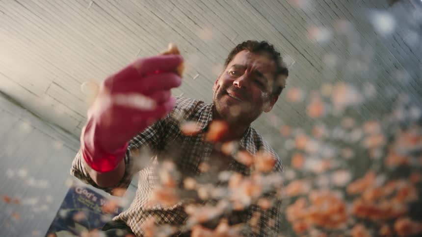 A man wearing pink gloves cleans a mess on a glass table as seen from below