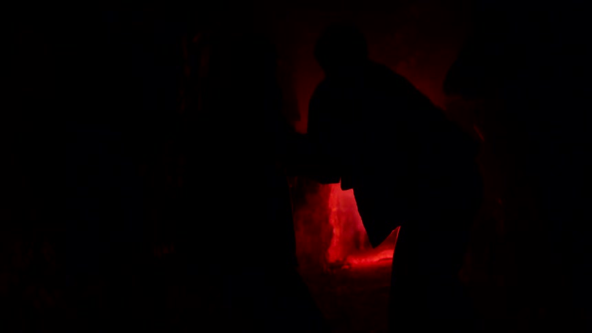 Friends standing in a tunnel are silhouetted by the light from the fireworks they are throwing