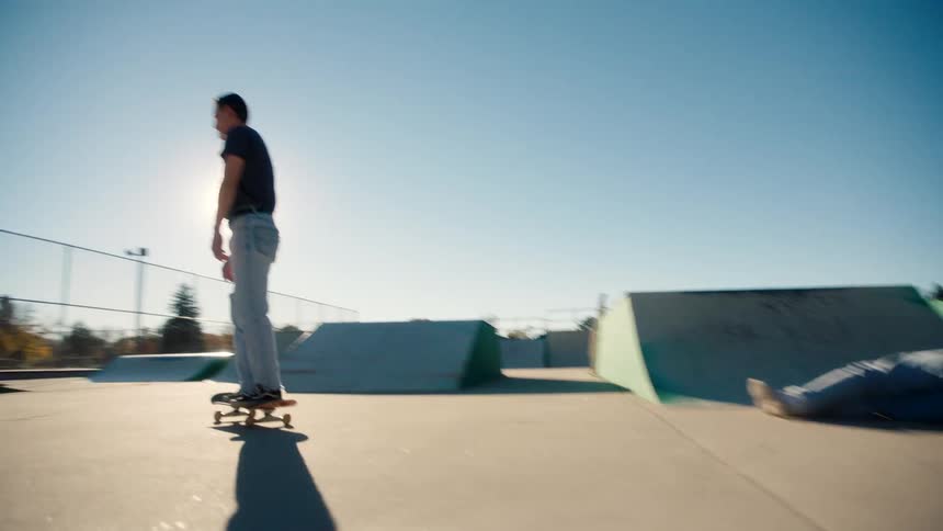 A teenager falls off his skateboard