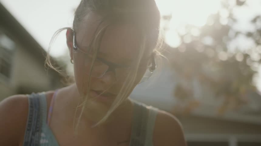 A girl is wearing sunglasses and standing in the backyard of house