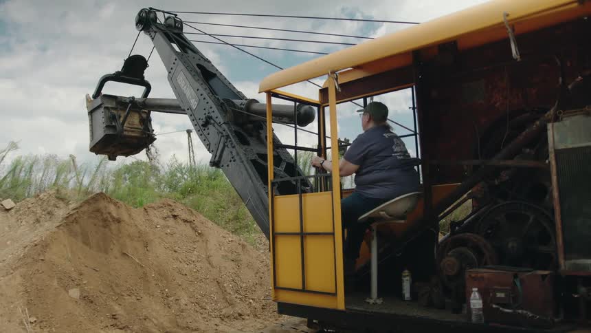 The excavator is living dirt from a pile