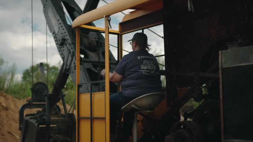 Woman sitting operating a construction tractor on a field