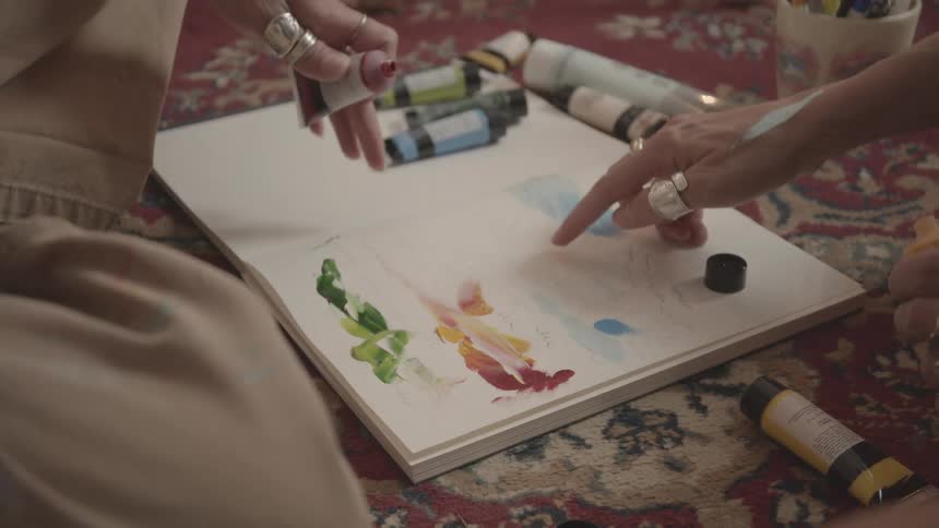 Two people are finger painting on a blank canvas