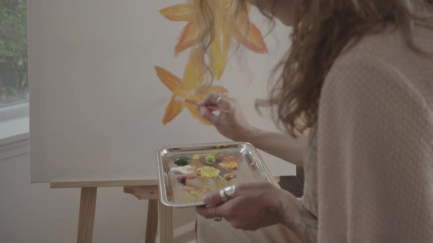 A woman is painting yellow flowers